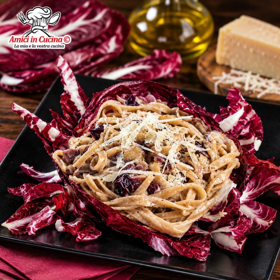 Piatto nero quadrato con tagliatelle di farro mantecate al formaggio e radicchio, servite scenograficamente all'interno di grandi foglie di radicchio crudo e spolverate di parmigiano, preparate da Maria Bruno
