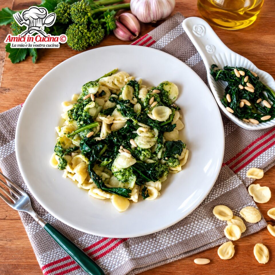 Piatto bianco con porzione di orecchiette condite con un cremoso pesto verde brillante di cavolo nero, guarnite con pinoli interi, adagiato su una tovaglietta a righe