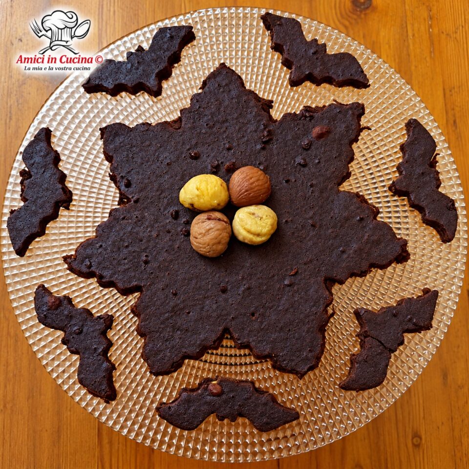 Torta al cioccolato a base di castagne frullate, sformata su un piatto di vetro decorato, circondata da biscotti a forma di pipistrelli ricavati dall'impasto stesso e guarnita con quattro castagne lesse al centro