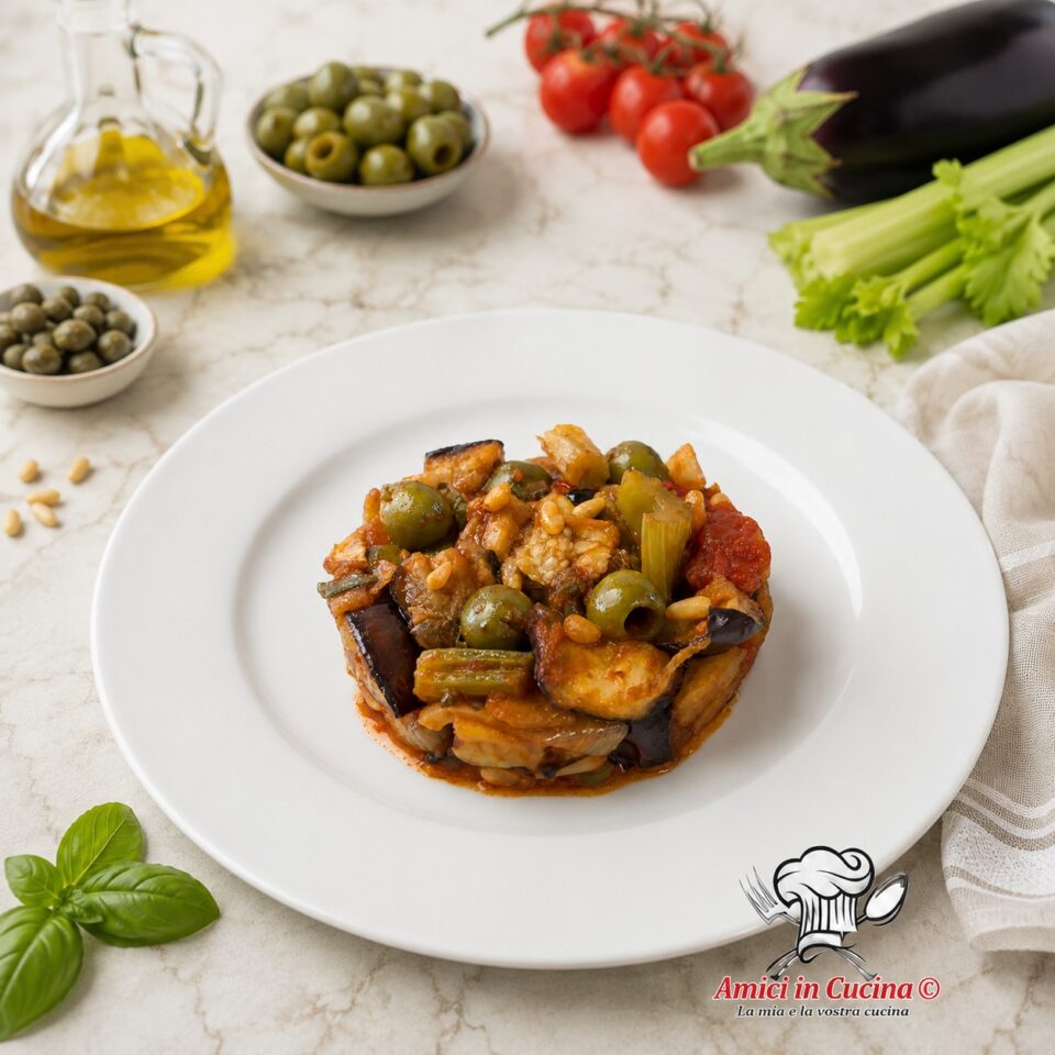 Caponata siciliana originale preparata con melanzane fritte, sedano, olive verdi, capperi, pomodorini e pinoli secondo la ricetta tradizionale.