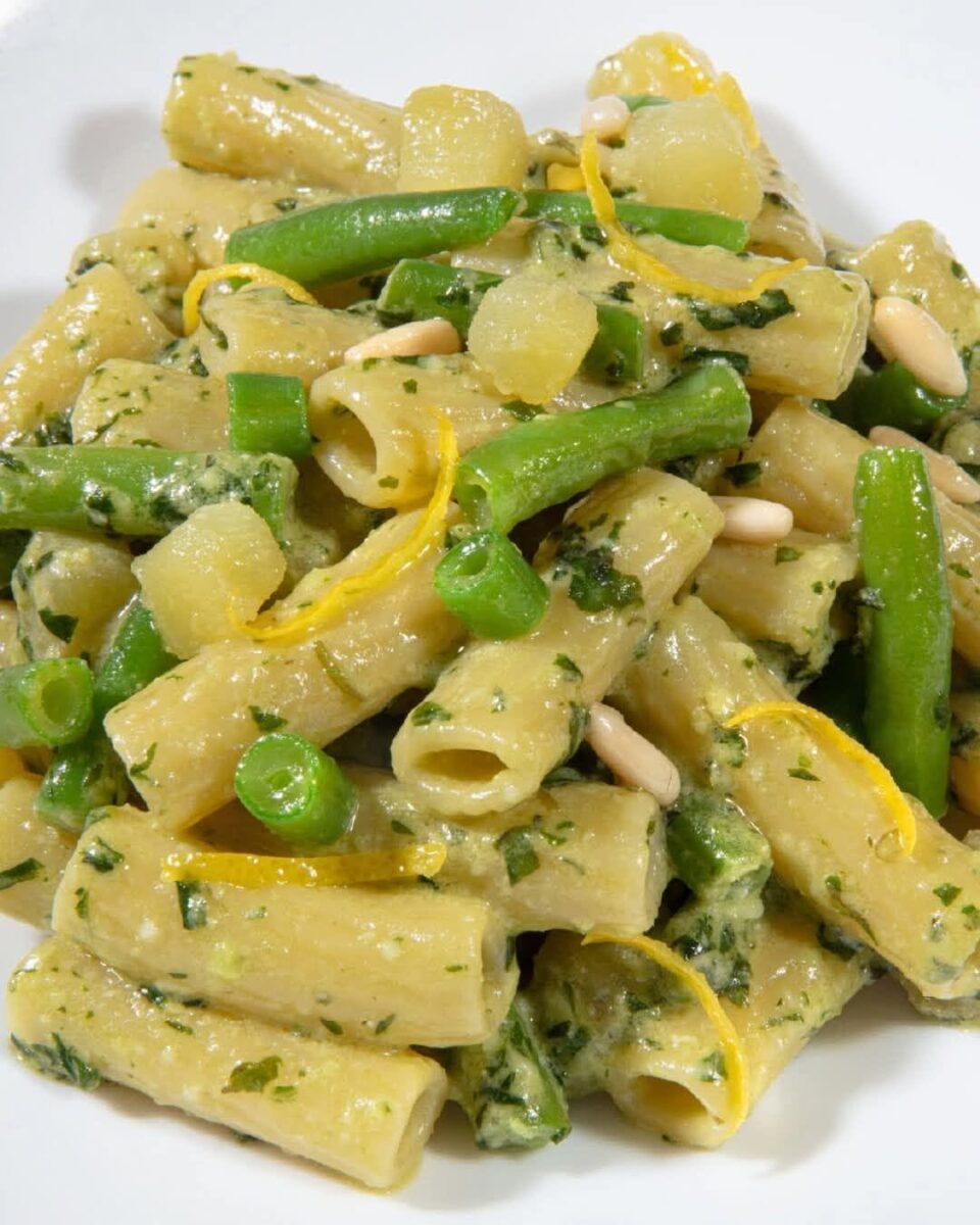 Primo piano dei tortiglioni con patate, fagiolini, basilico e pinoli.