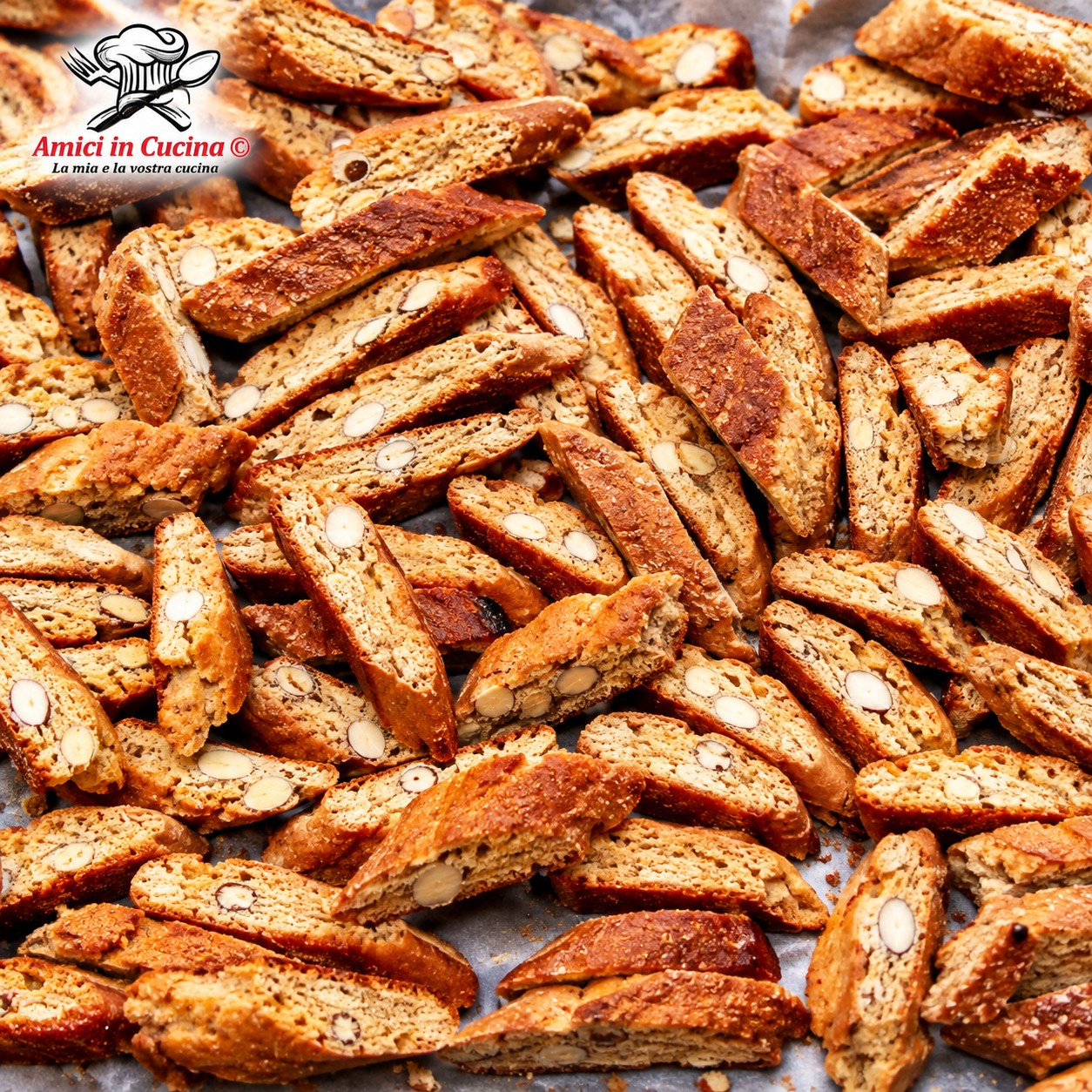 Vassoio di legno con fragranti cantucci alle mandorle dorati appena sfornati, affiancati da un bicchierino di Vin Santo: