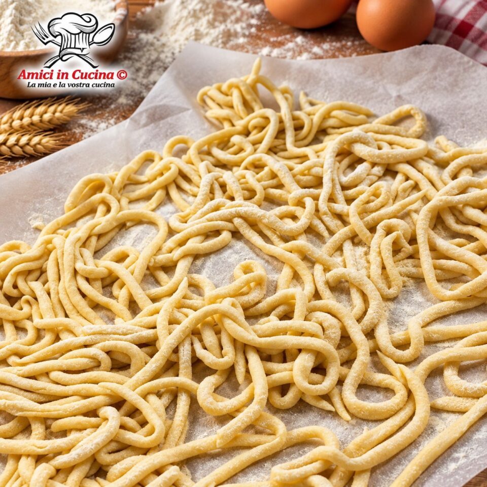 Spianatoia di legno infarinata con lunghi e spessi spaghettoni di pasta fresca senza uova chiamati lombrichi
