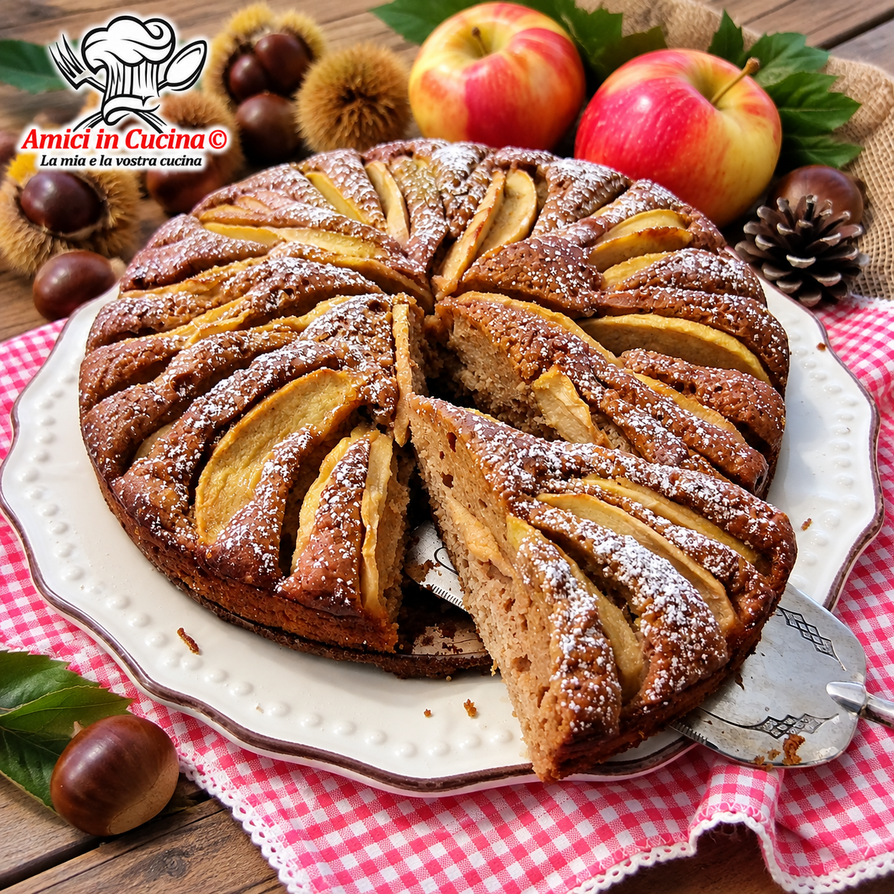 Una fetta di torta rustica e soffice a base di farina di castagne, ricca di mele e spolverata di zucchero a velo, sollevata da una paletta per dolci con sfondo a quadretti rossi