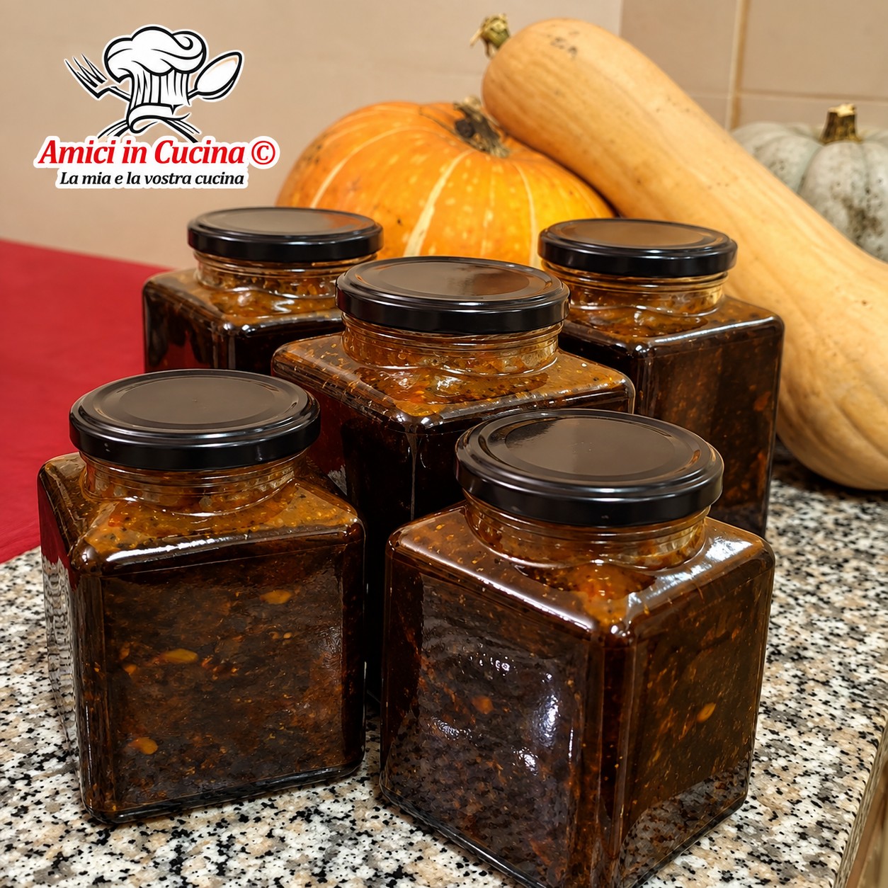 Vasetti di vetro riempiti con la saba, uno sciroppo scuro e denso a base di mosto d'uva cotto, con una zucca autunnale sullo sfondo