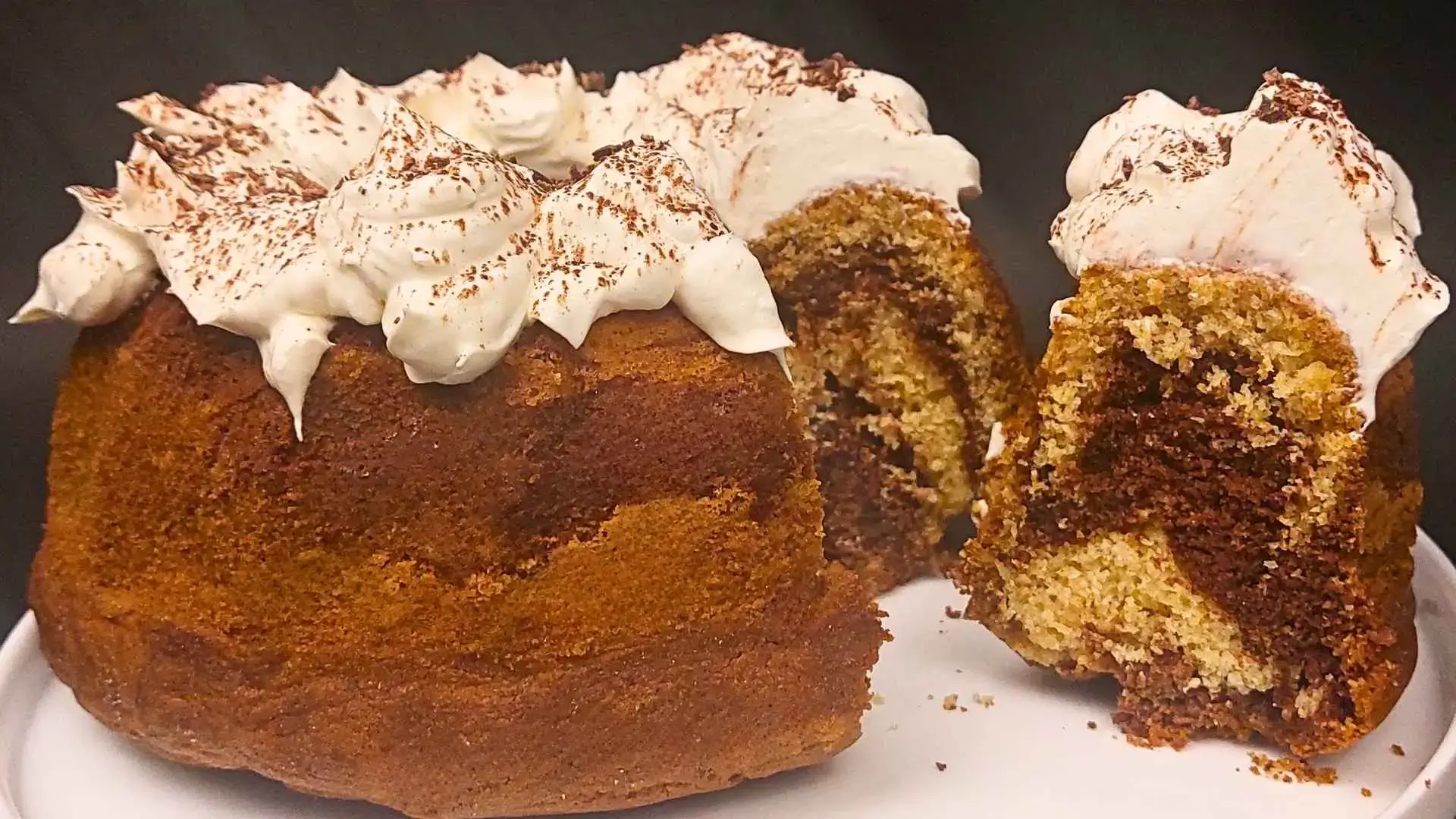 Torta marmorizzata cacao e caffè con sopra crema al mascarpone c'è anche una fetta sul piatto bianco