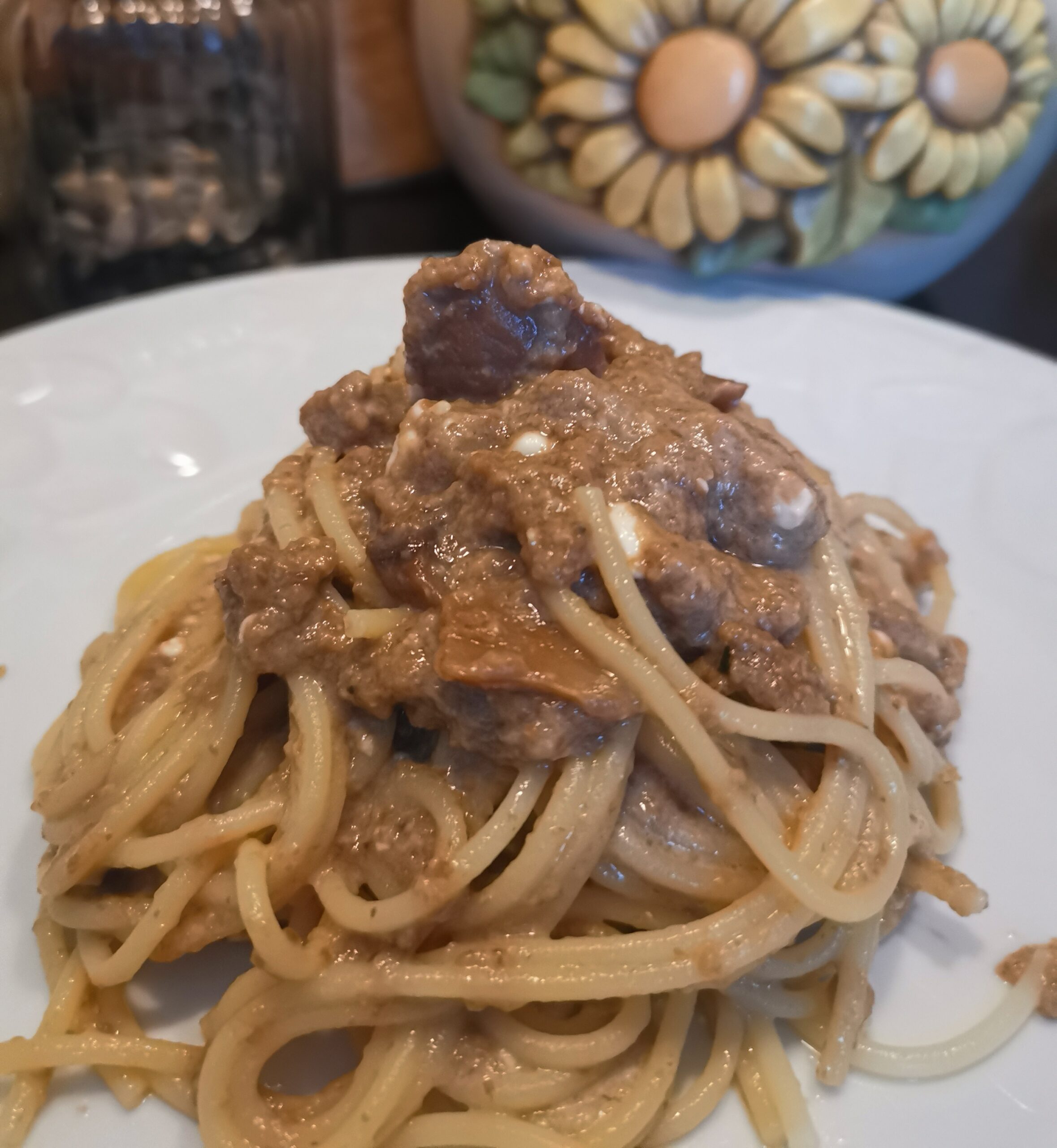 Piatto di spaghetti d'autunno cremosi ai funghi e fiocchi di latte servito in un piatto bianco
