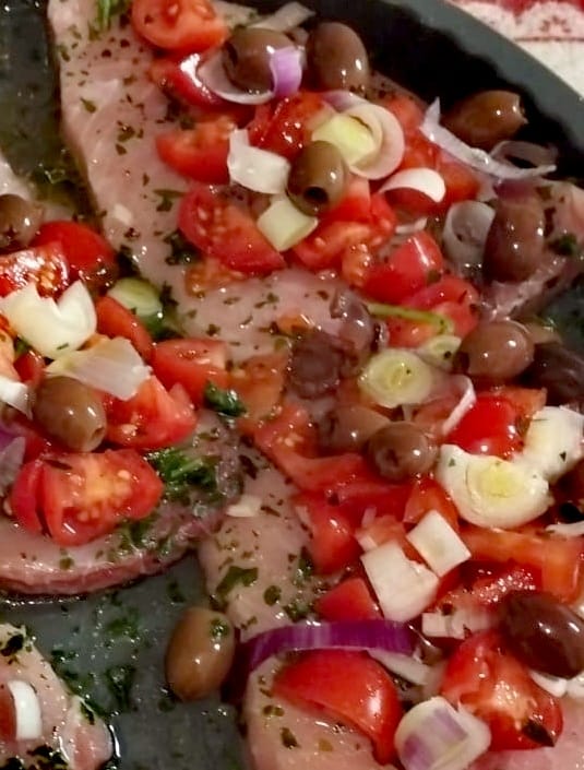 Dettaglio del pesce spada al forno con pomodorini olive e cipollotto