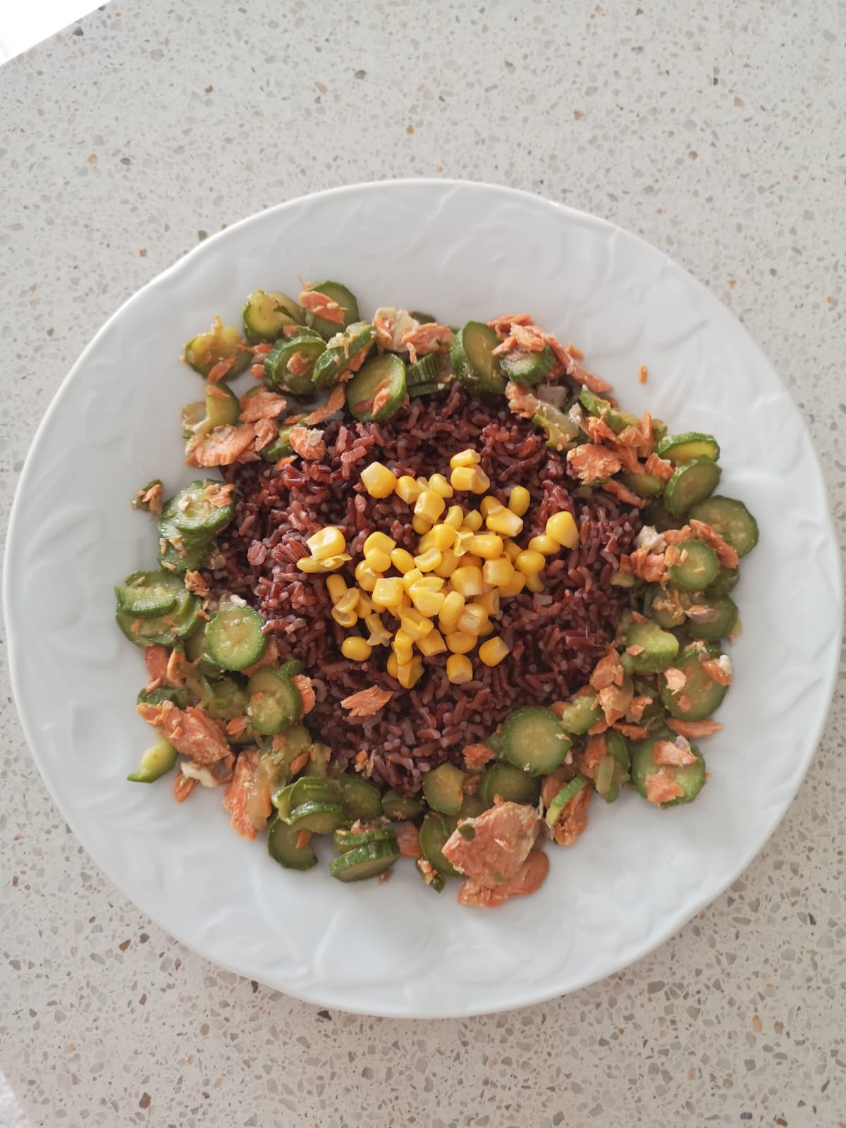 Piatto di riso rosso integrale con salmone, zucchine e mais dolce