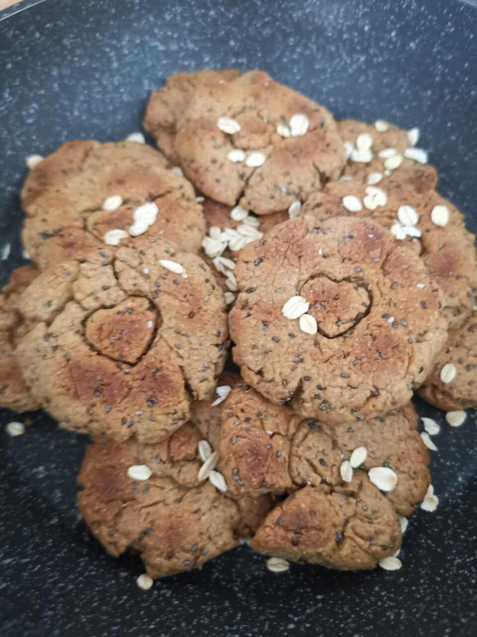 Biscotti in padella friabili all'avena pronti all'interno della padella e decorati con fiocchi d'avena sparsi