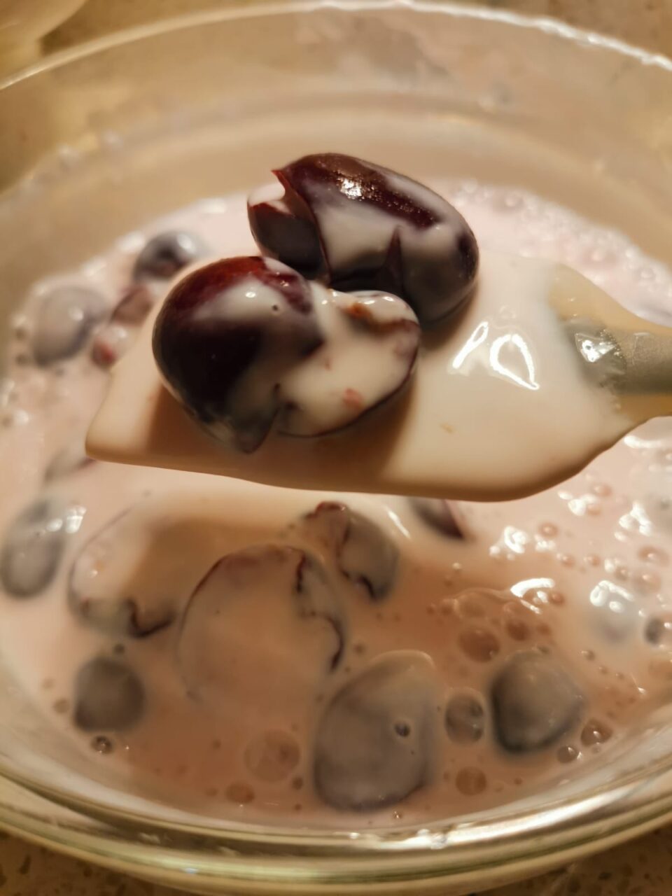 Dettaglio ravvicinato di ciliegie snocciolate mescolate con yogurt greco e latte per porridge freddo