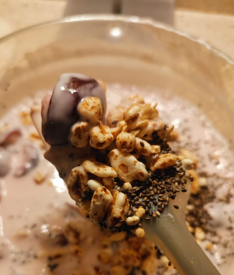 Primo piano di una spatola con porridge freddo alle ciliegie, semi di chia e farro soffiato croccante