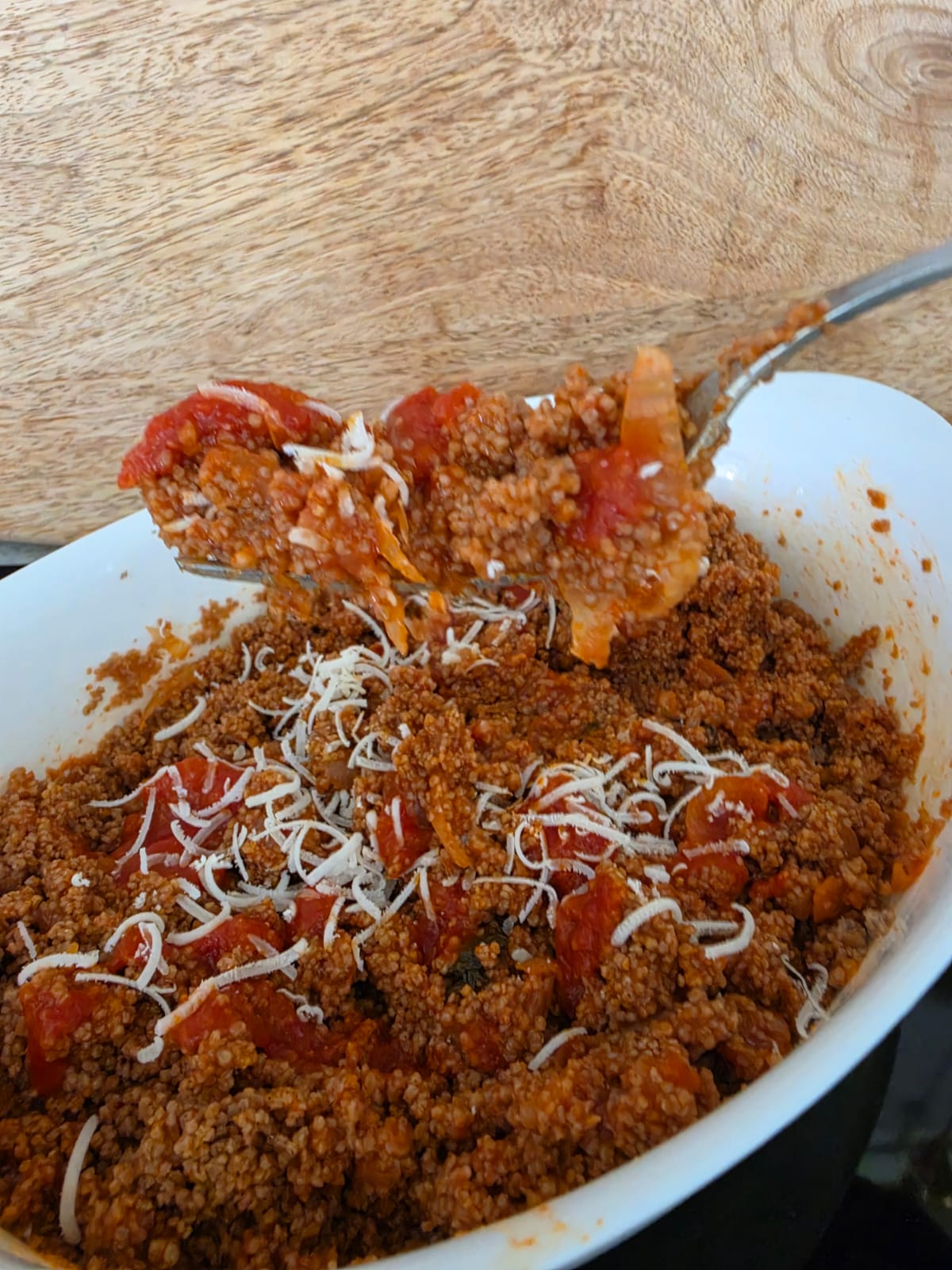 Piatto di couscous di grano saraceno senza glutine condito con sugo di pomodoro fresco, basilico e parmigiano grattugiato.