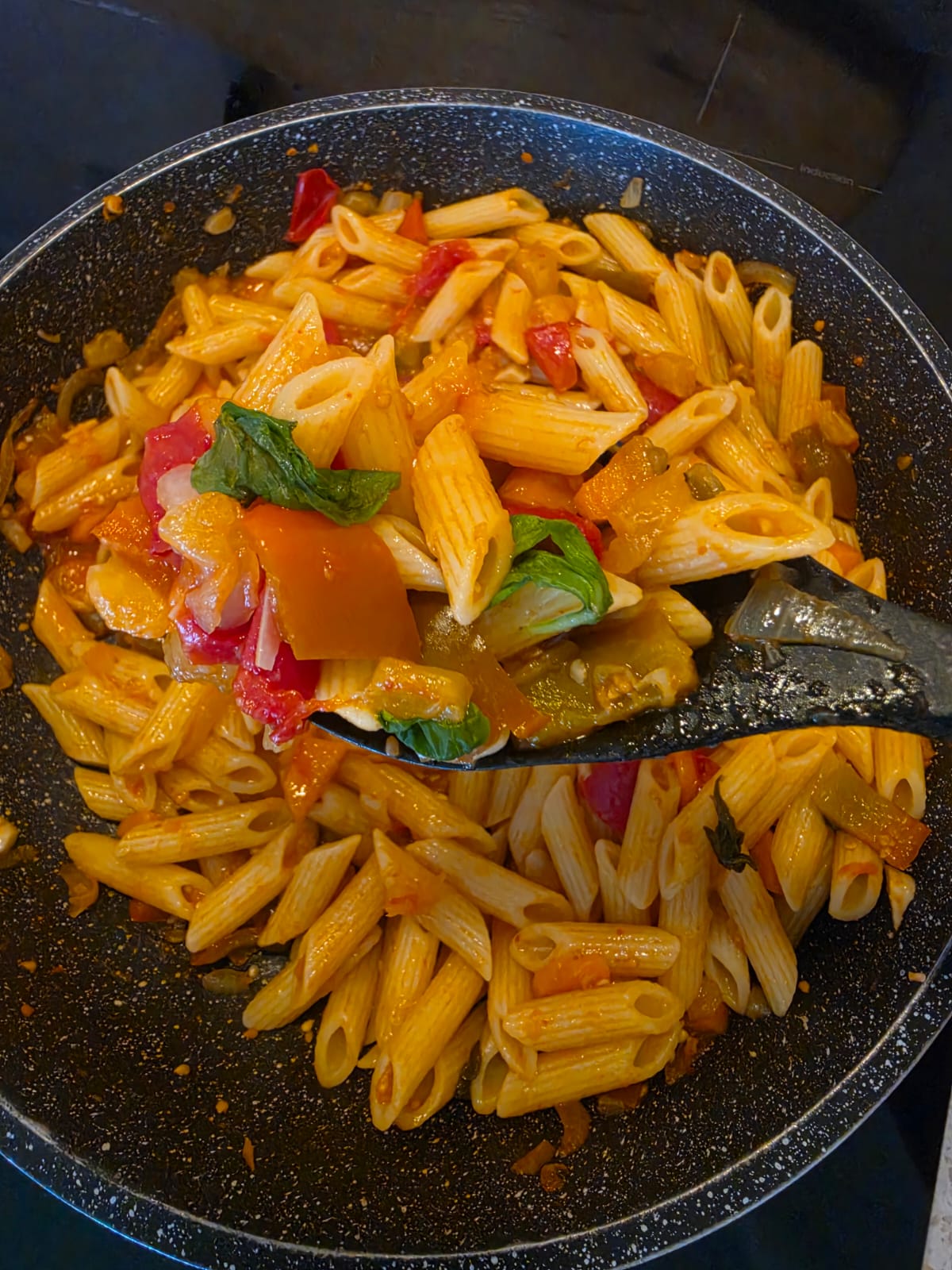 Padella con pasta mantecata con sugo di verdure estive, melanzane, pomodorini e foglie di basilico fresco