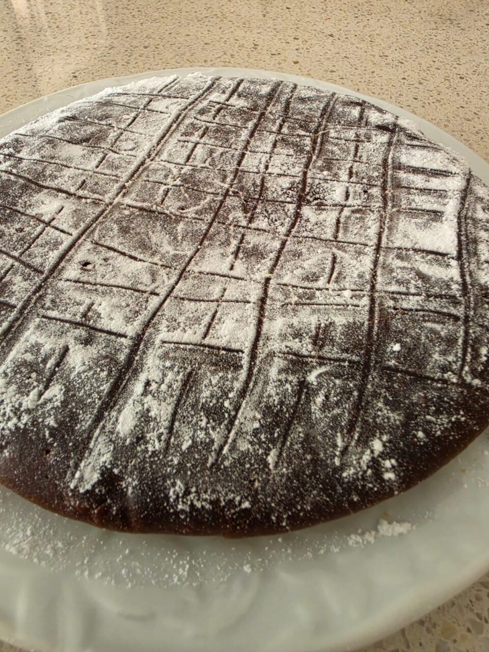 Torta al cioccolato cotta in padella senza uova vista dall'alto spolverizzata con zucchero a velo
