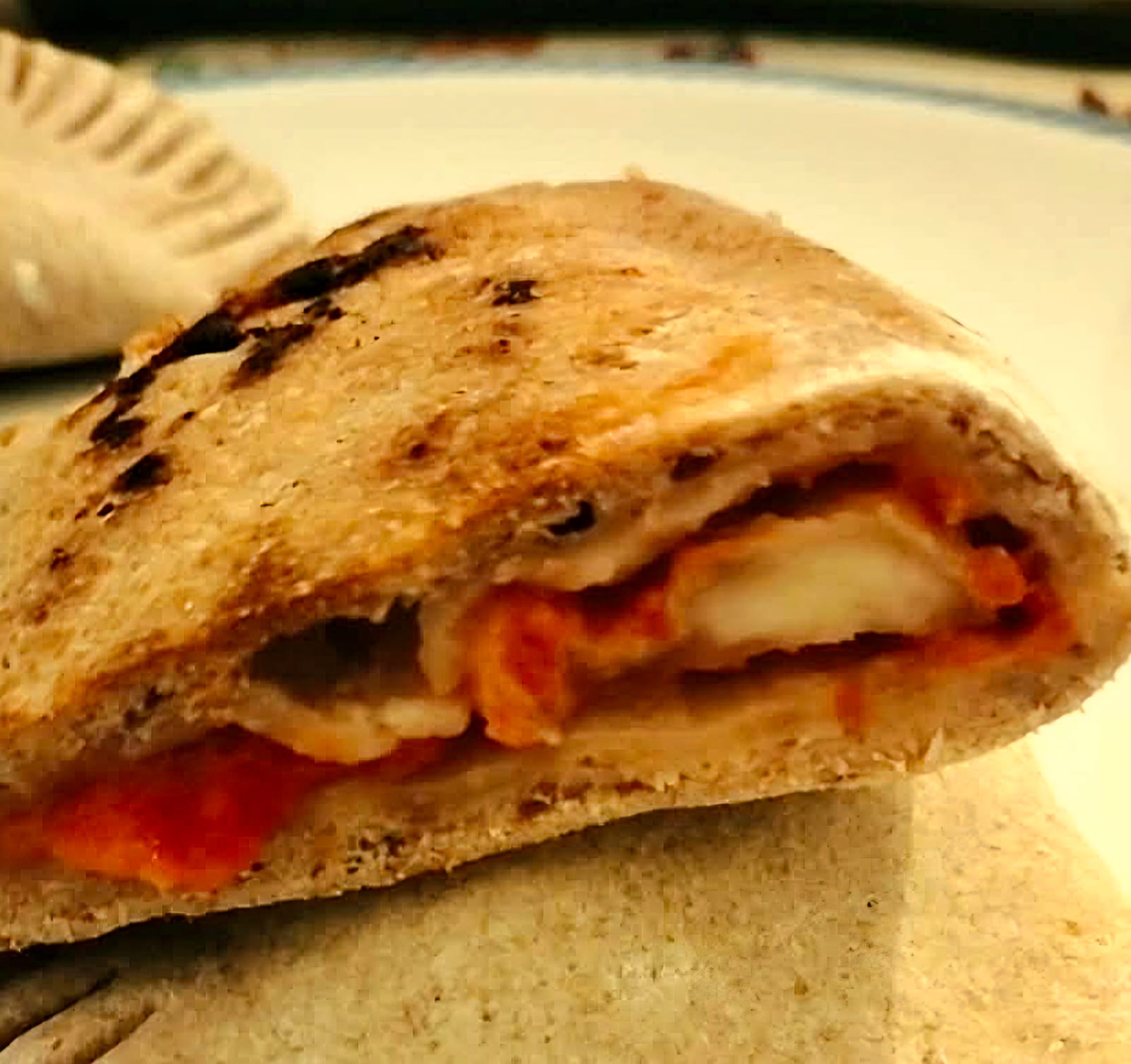 Calzone aperto a metà con impasto proteico ai fagioli e farro, ripieno di sugo di pomodoro e mozzarella filante.