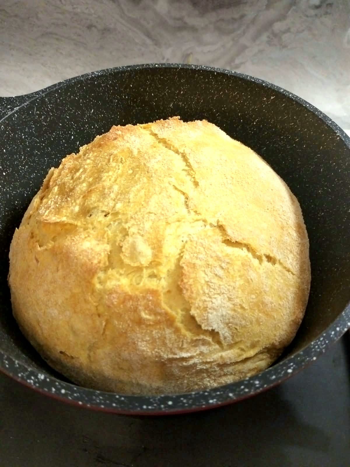 Pagnotta di pane alla zucca cotto in pentola con crosta dorata e spaccature croccanti.
