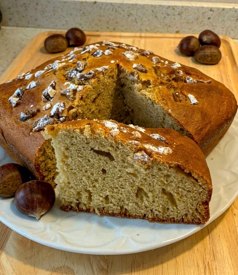 Fetta di torta soffice con castagne e kefir senza burro servita su un piatto con castagne dolci sul tagliere