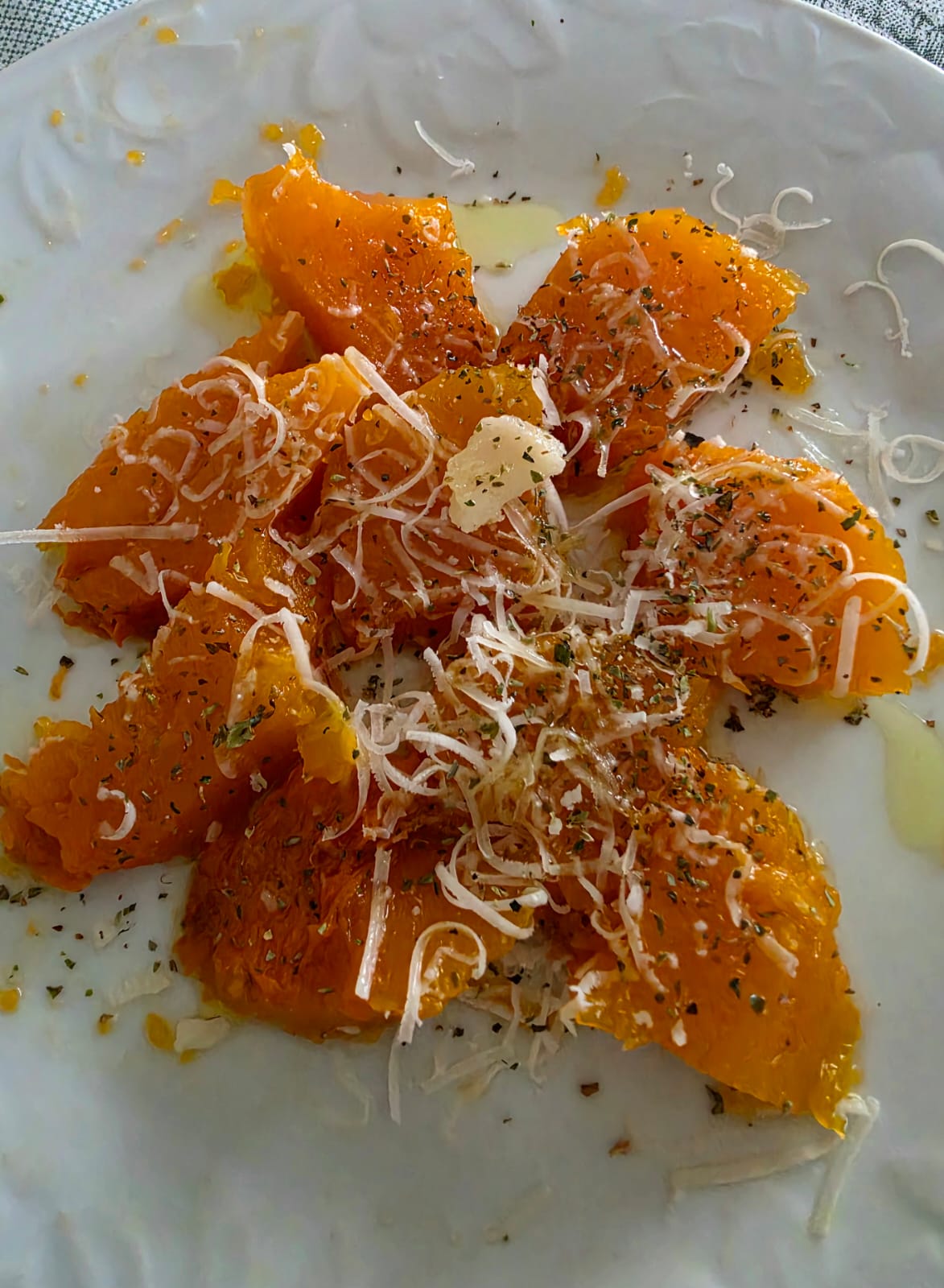 Piatto con bocconcini di zucca al forno saporita senza grassi condita con erbe aromatiche e formaggio.