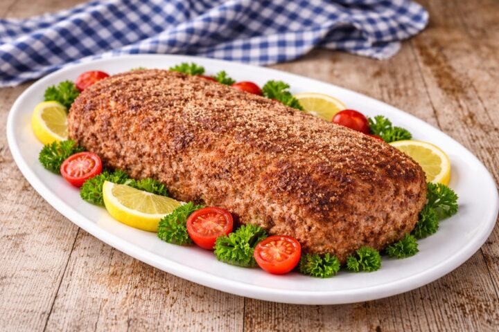 Polpettone cotto intero con superficie dorata su piatto ovale