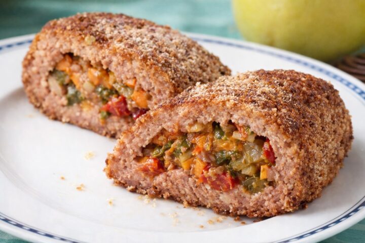 Due fette di polpettone cotto con ripieno di verdure su piatto bianco