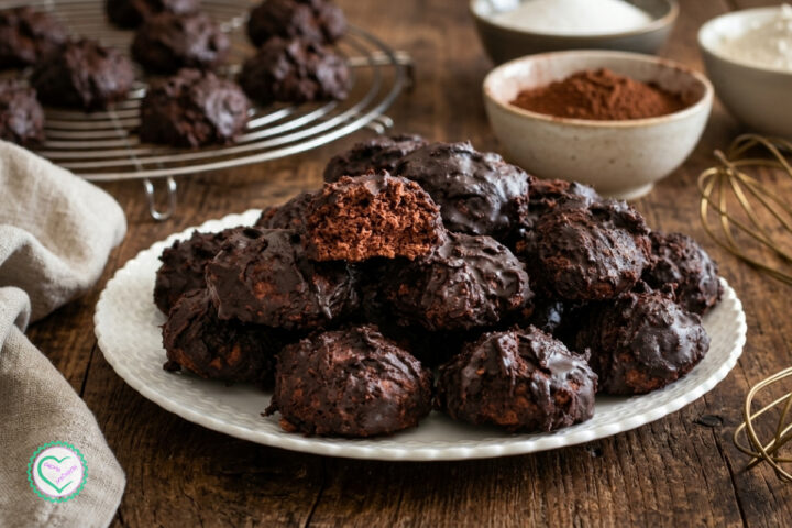 Biscotti Totò catanesi con glassa al cacao su un piatto bianco, con un biscotto spezzato che mostra l’interno poroso