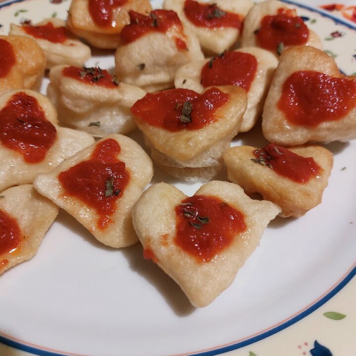 Pasta a forma di cuore con olive in ciotola di legno.