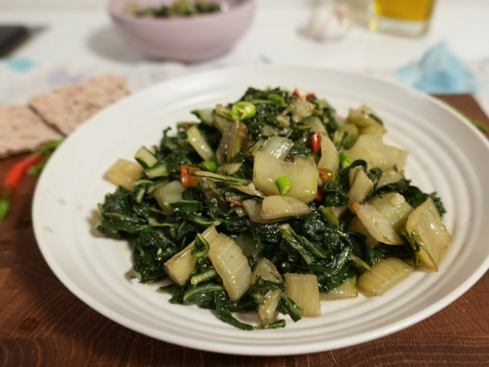 Primo piano del piatto di bietole appena impiattato, che mostra le diverse consistenze di coste e foglie e la lucentezza dell'olio.