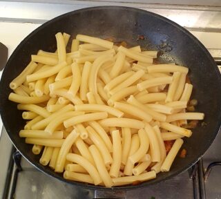 aggiunt della pasta cotta e scolata al sugo di peperoni e nduja