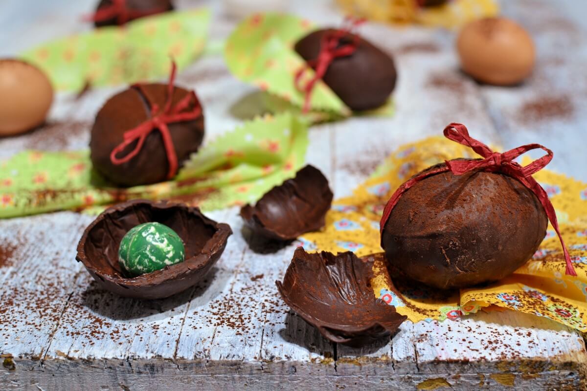 Ovetti di cioccolato fatti in casa su piano bianco, uno aperto con sorpresa