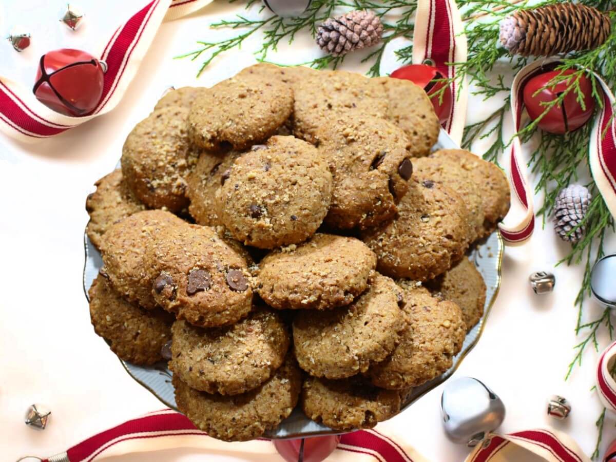 Biscotti natalizi alle nocciole e cannella Dolcipocodolci su piatto bianco con decorazioni rosse natalizie