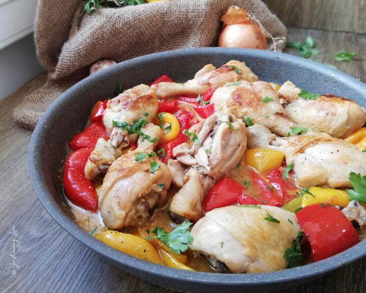 Fusi di pollo ai peperoni in padella senza pomodoro serviti caldi in una casseruola, con peperoni rossi e gialli cremosi.