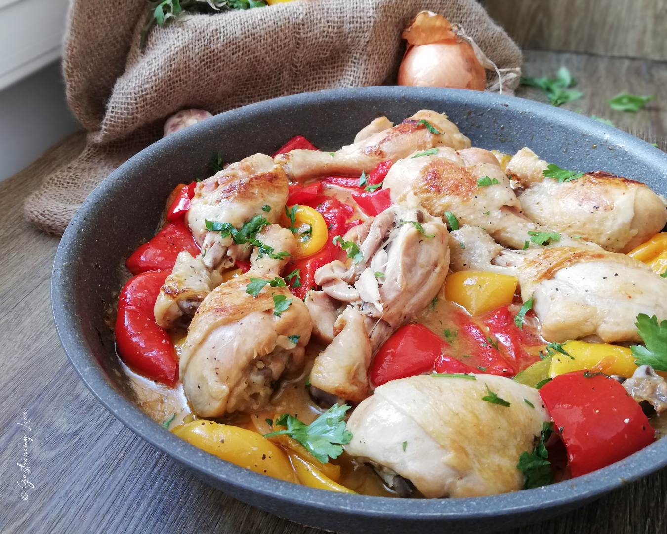 Fusi di pollo ai peperoni in padella senza pomodoro serviti caldi in una casseruola, con peperoni rossi e gialli cremosi.