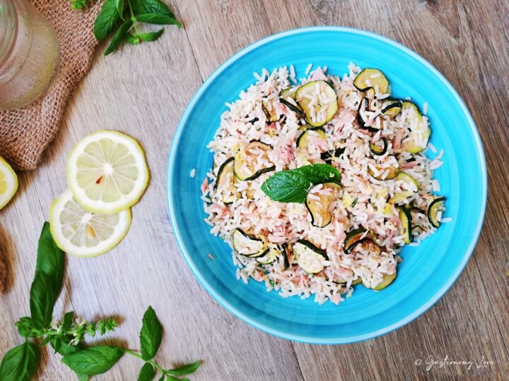 Primo piano di un'insalata di riso estiva con filetti di tonno, zucchine a rondelle cotte in friggitrice ad aria e menta.