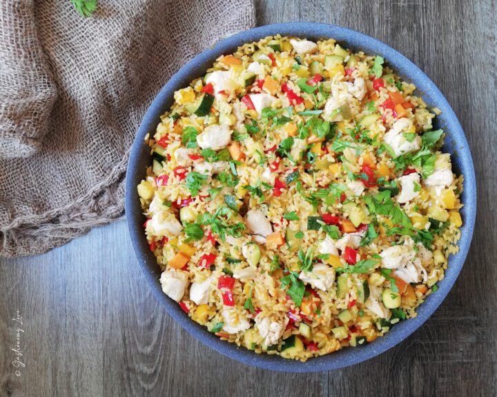 Riso con pollo e verdure alla marocchina cotto in una casseruola capiente, arricchito con prezzemolo fresco tritato e spezie profumate