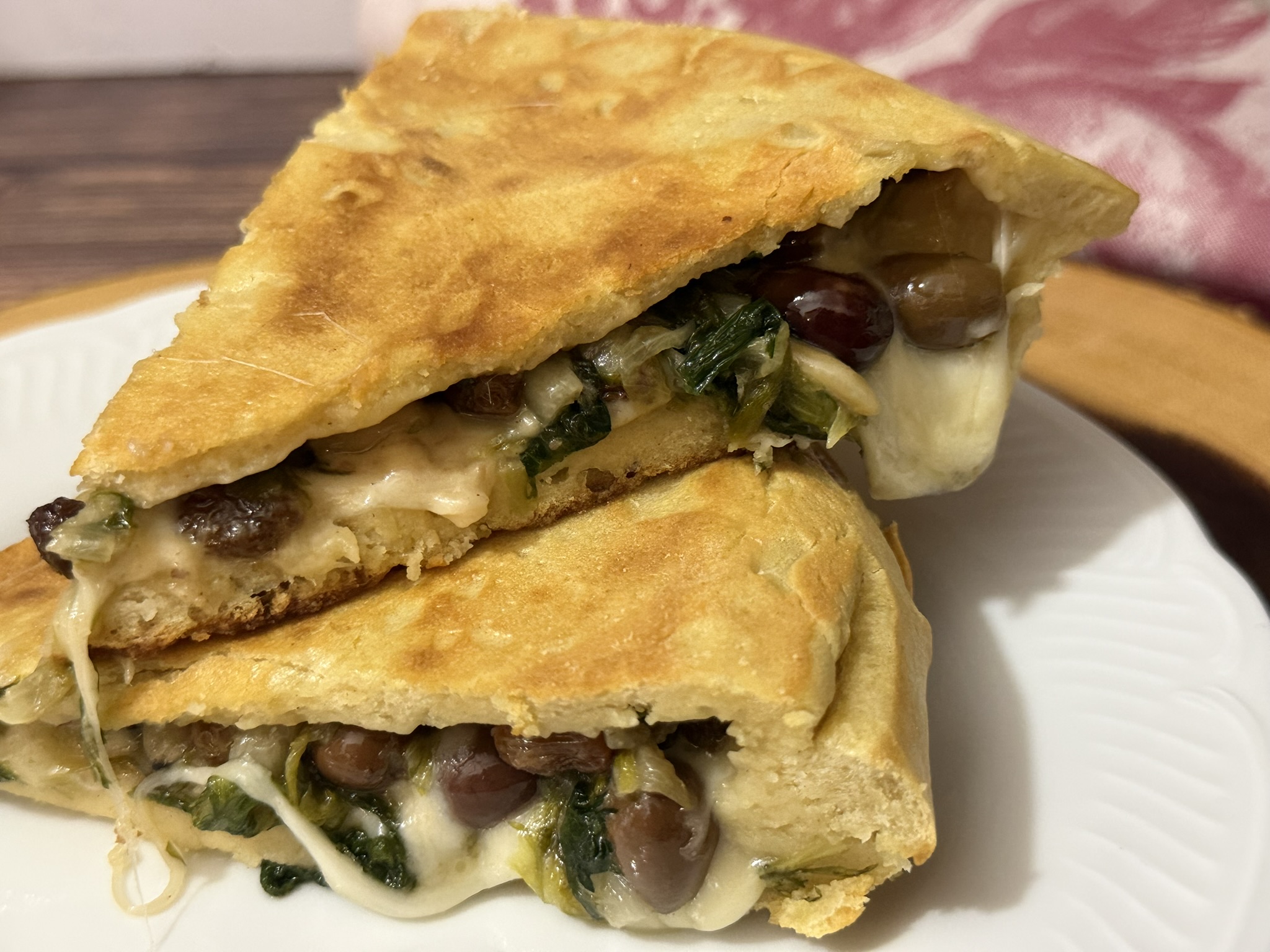 Fetta di pizza di scarola senza lievito in padella ricetta veloce senza forno, base dorata e croccante con ripieno filante di provola, scarola, uvetta e pinoli.