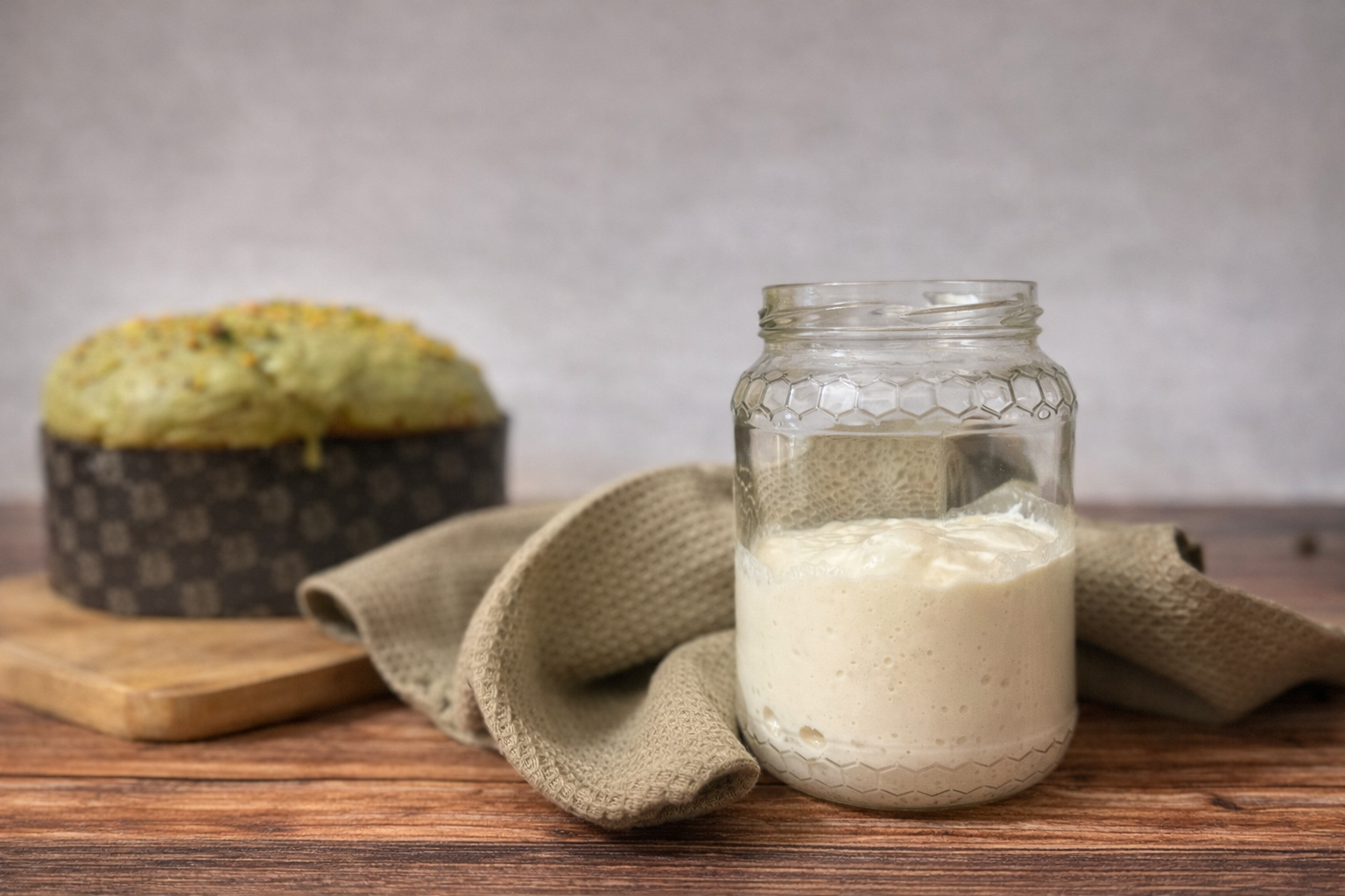 Lievito madre liquido licoli con bolle di fermentazione in barattolo di vetro su piano in legno.