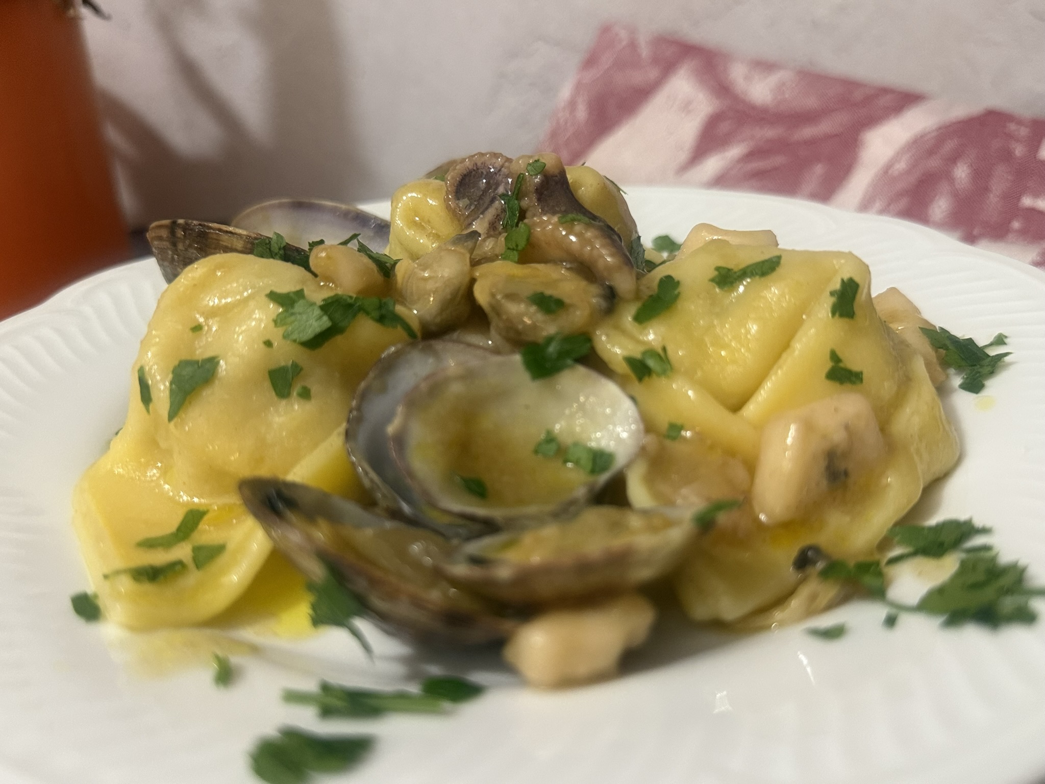 Tortelloni ripieni di pesce con vongole e calamari primo piatto di mare serviti su piatto bianco