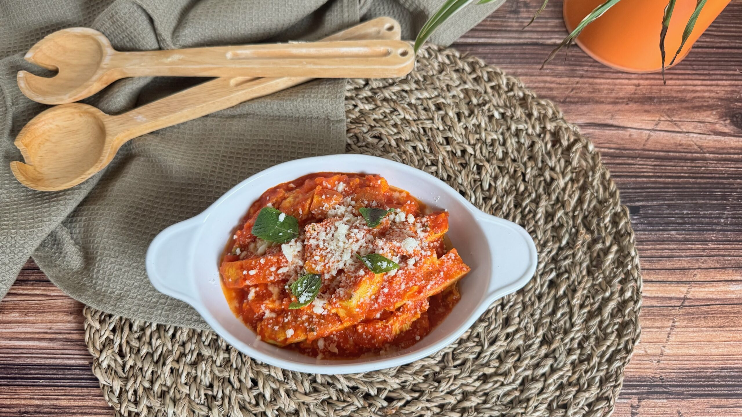 Finta trippa alla romana con le uova, ricetta originale della tradizione: striscioline di frittata condite con sugo di pomodoro, pecorino romano grattugiato e foglie di menta fresca, servite in un piatto bianco e accompagnate da fette di pane rustico.