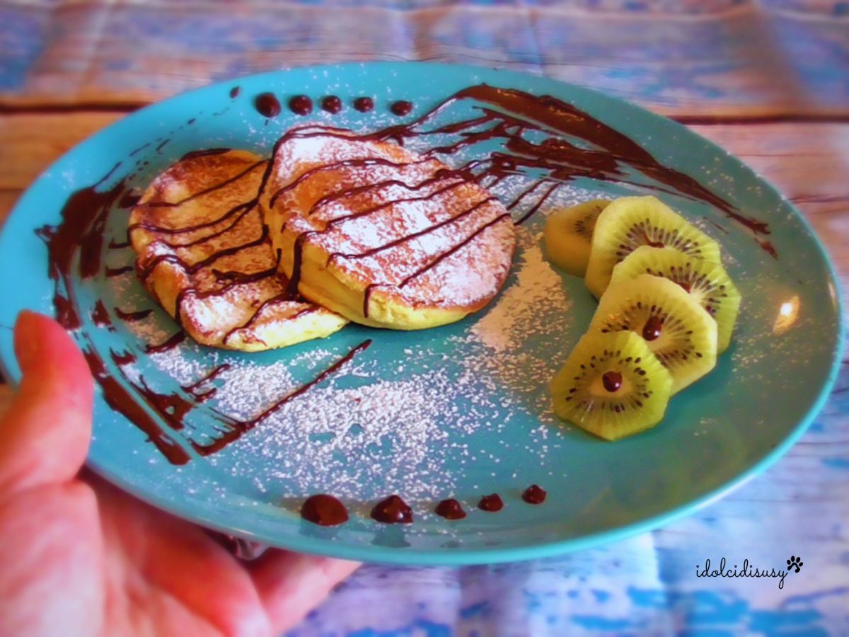 Pancake soufflé giapponesi alti e soffici serviti con zucchero a velo, cioccolato e kiwi