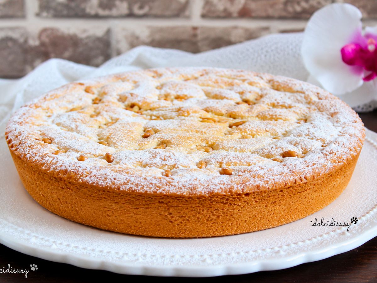Torta della nonna fatta in casa con crema pasticcera, pinoli e zucchero a velo servita su piatto bianco