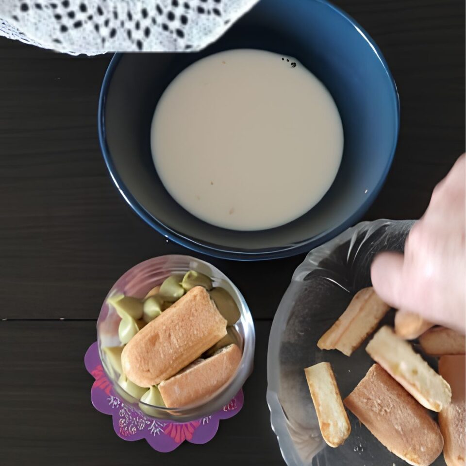 Savoiardi bagnati nel latte e disposti nel bicchiere per preparare il tiramisù al bicchiere
