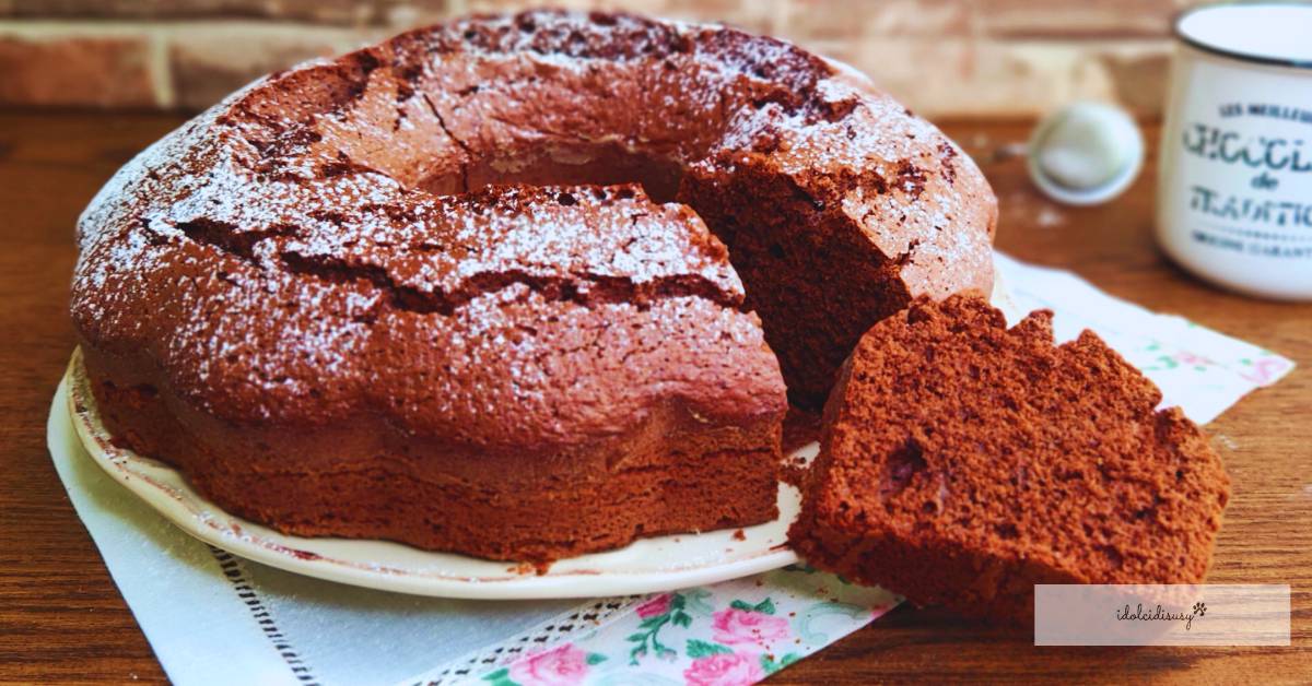 Ciambellone al cioccolato Bimby soffice, spolverato con zucchero a velo e servito su un piatto bianco