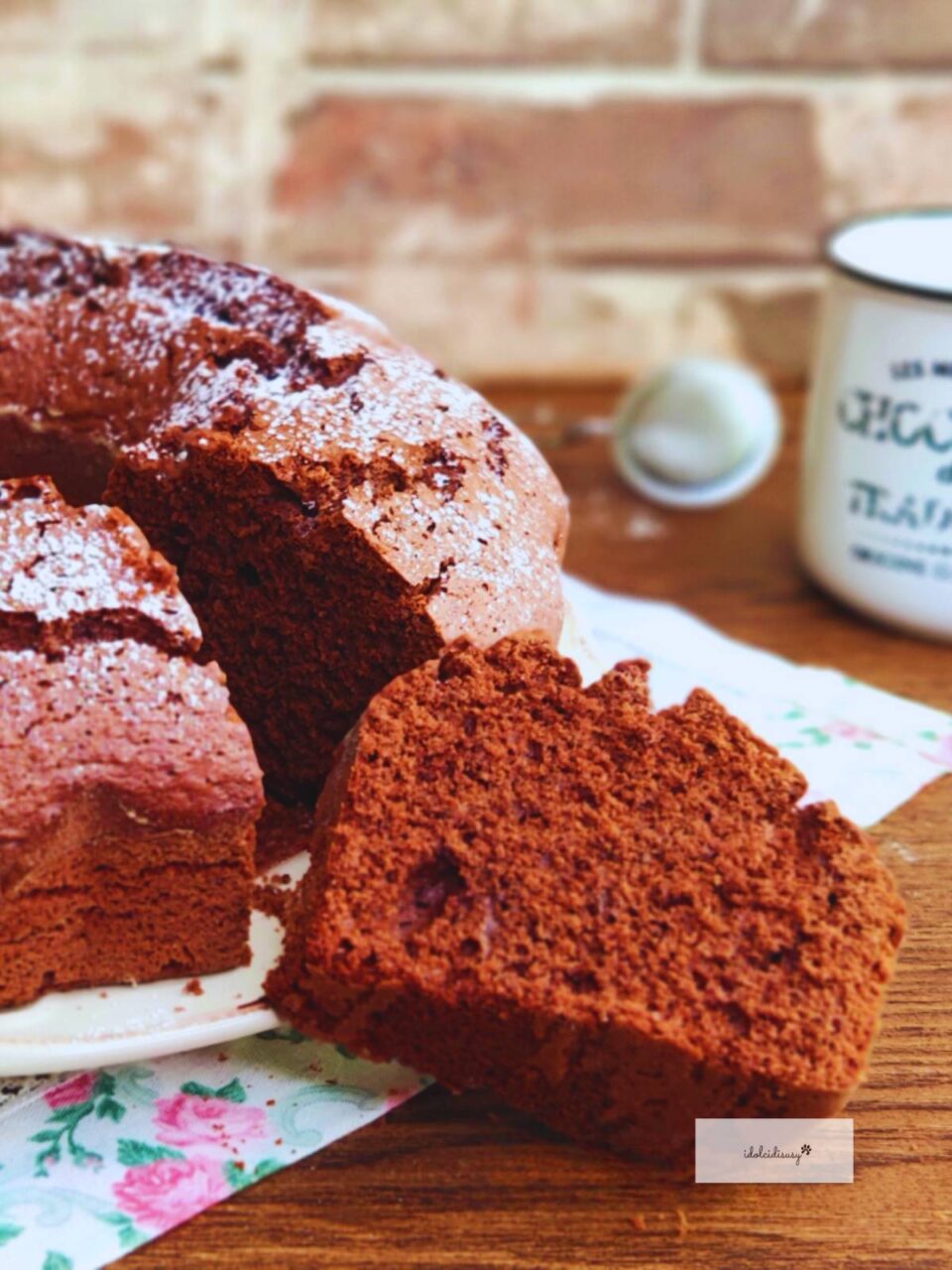 Fetta di ciambellone al cioccolato Bimby soffice e morbida in primo piano, con zucchero a velo sulla superficie