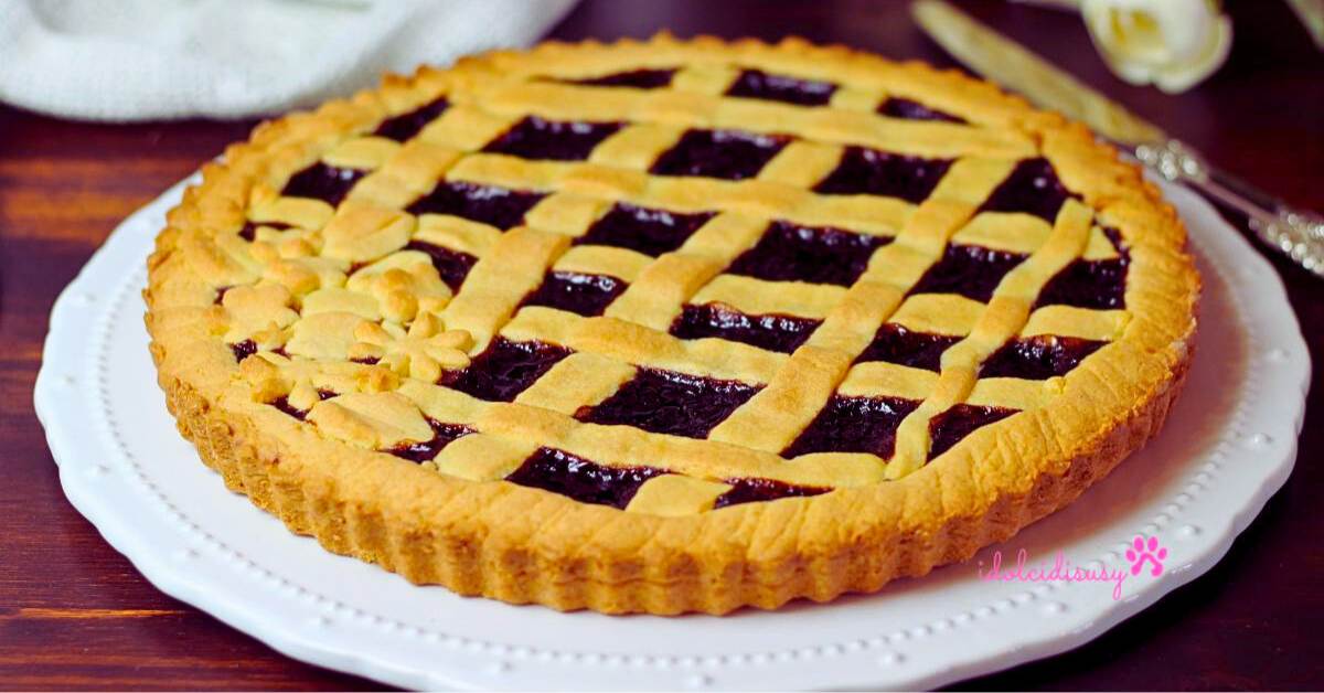 crostata alla marmellata fatta in casa di ciliegie con griglia di frolla e bordo lavorato, servita su piatto bianco