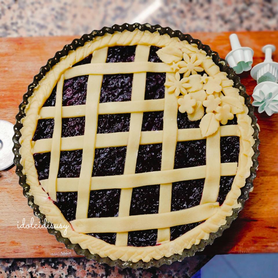 Crostata alla marmellata pronta da infornare, con losanghe e decorazioni floreali in frolla