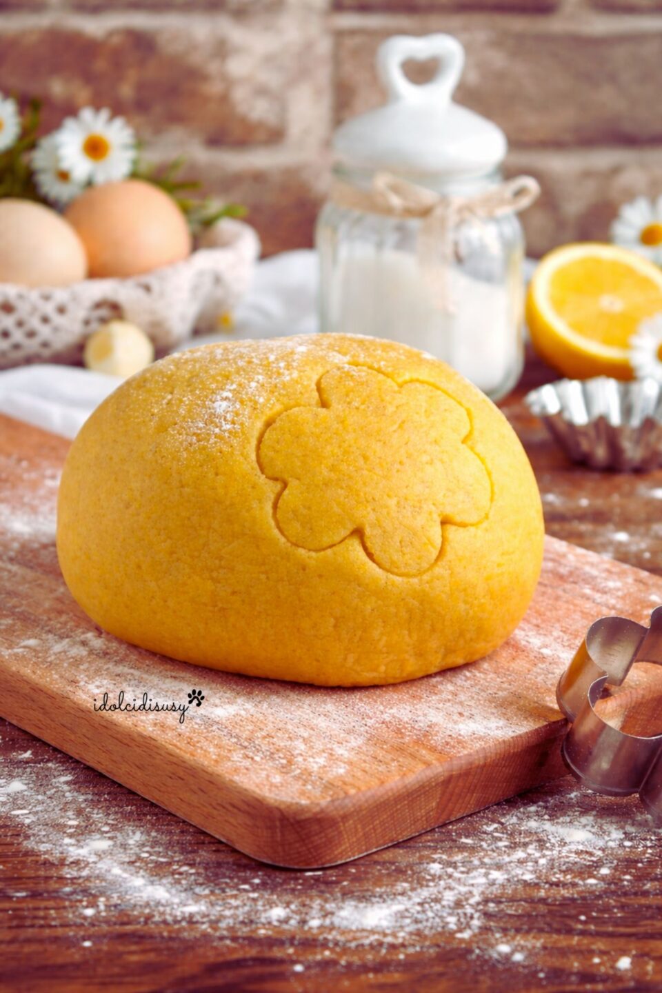 Impasto di pasta frolla fatto in casa sul tagliere di legno con stampino a fiore e farina