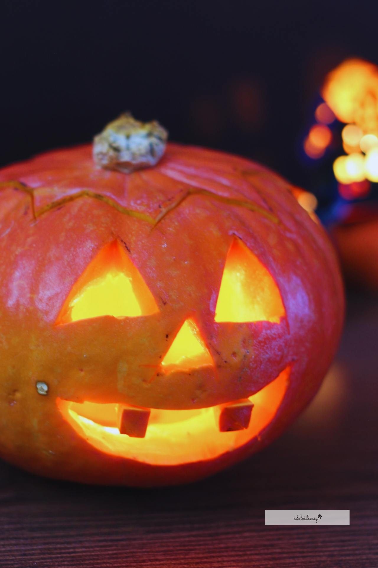 Zucca di Halloween con candelina accesa all’interno, intagliata con occhi triangolari e sorriso
