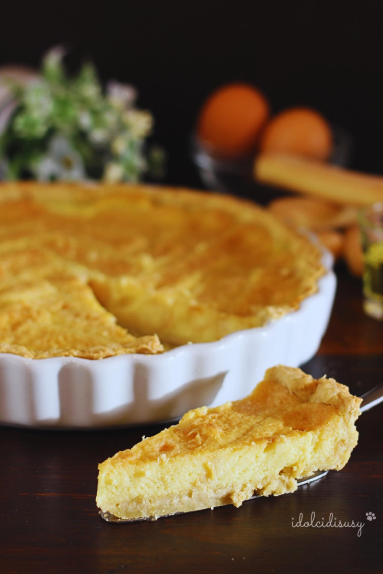 Fetta di crostata beneventana in primo piano con base di frolla, savoiardi e crema al liquore Strega