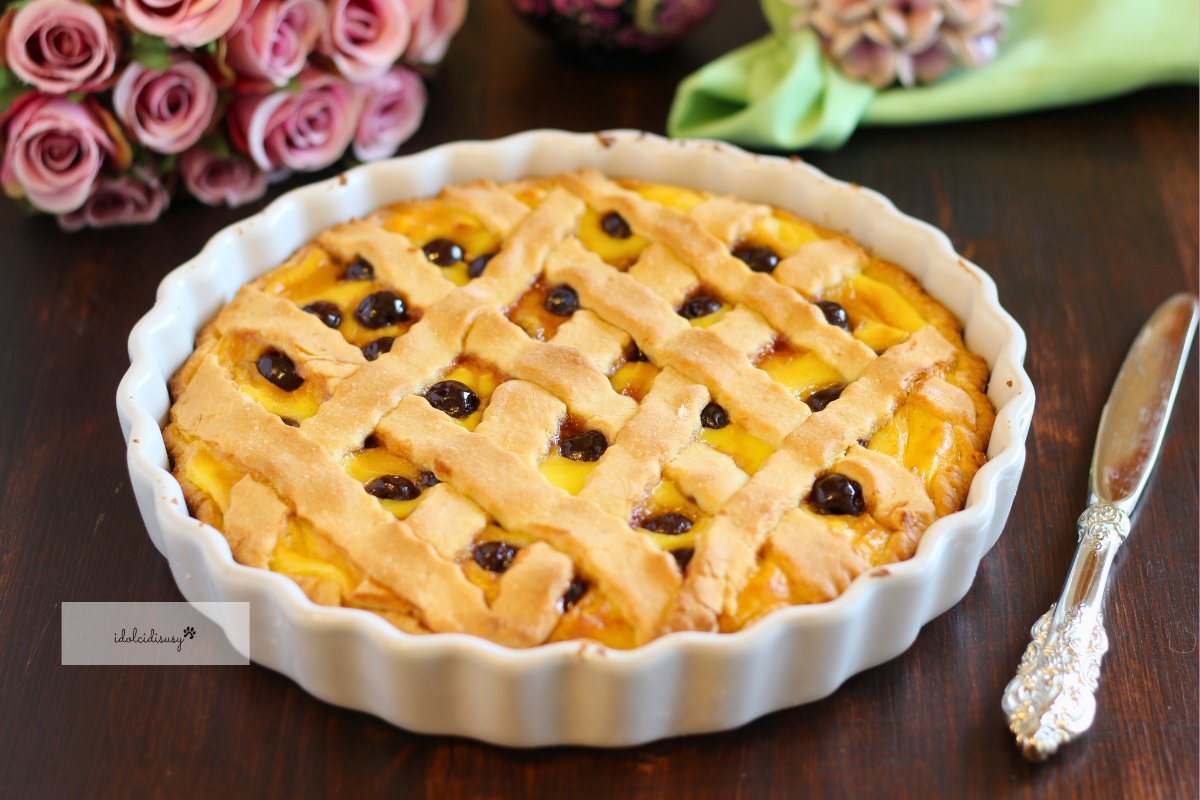 Crostata crema e amarene intera in ceramica bianca, pronta da servire con crema pasticcera e amarene sciroppate
